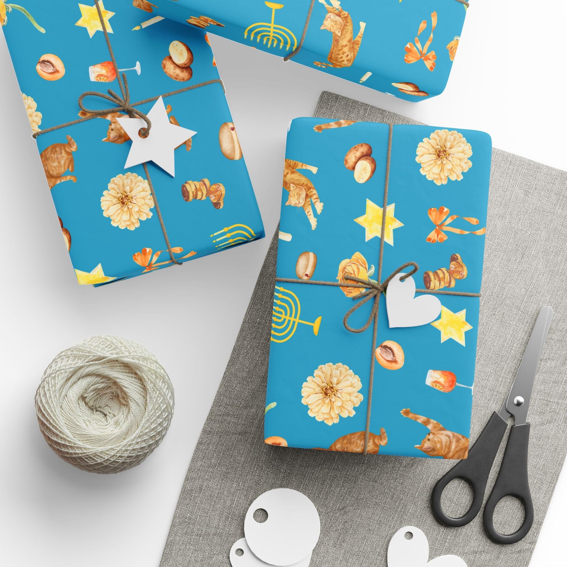 Blue Hanukkah gift wrap with whimsical pattern of orange cats and golden menorahs