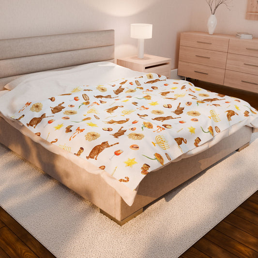White Hanukkah throw blanket featuring orange cats, brass menorahs, and gold flowers on a queen bed