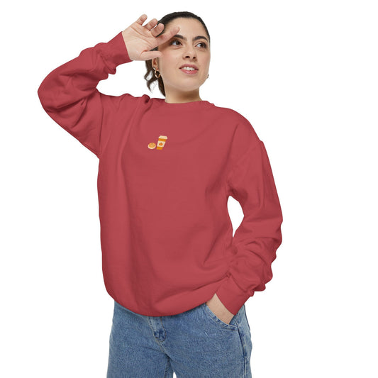 Woman wearing a red sweatshirt with a small embroidered design of autumn cookie and pumpkin spice latte